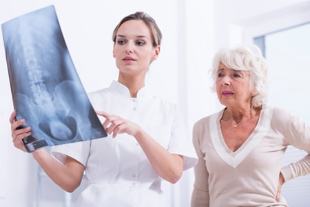 el médico indica a la paciente una radiografía de la columna vertebral
